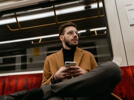 Man met smartphone op trein.